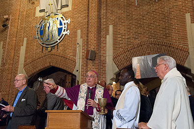 Bishop Dimarzio with an aspergillum in his hand blessing the restored Kilgen Pipe Organ at Our Lady of Refuge with Holy Water